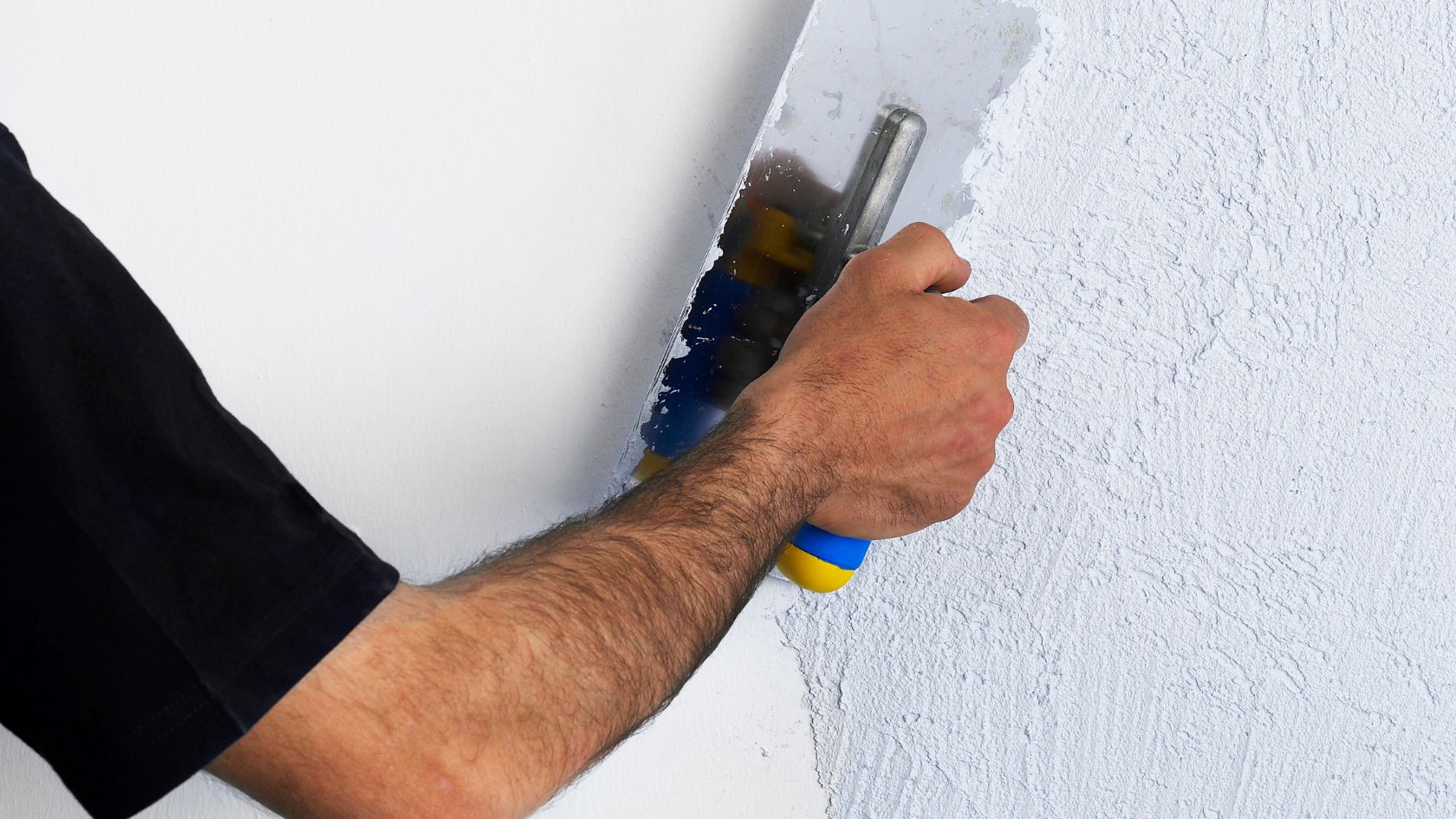 Website%20Dev.%20-%202025-07-02T154521.711 a person's arm using a scraper to apply spcakle to a wall